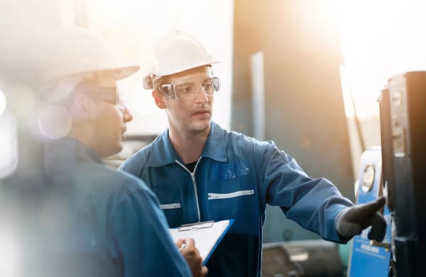 Packaging system Two male factory workers in safety gear reviewing a packaging or automation system.