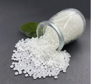 Packaging system White bio-based adhesive pellets spilling from a glass jar onto a dark surface